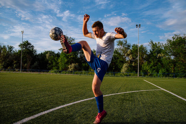 Young male soccer player juggles a ball on a soccer field.Athlete juggling the football with his feet in stadium.Football sports concept