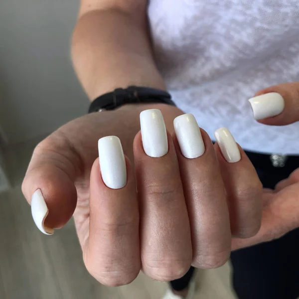 Woman\'s hands with white. Nail varnishing in white color. Manicure beauty salon concept. Empty place for text or logo.