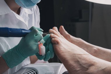 Hırdavat pedikür. Elektrikli makine kullanan profesyonel donanım pedikürü. Maske ve eldiven yapımında uzman. Güzellik salonunda pedikür süreci.