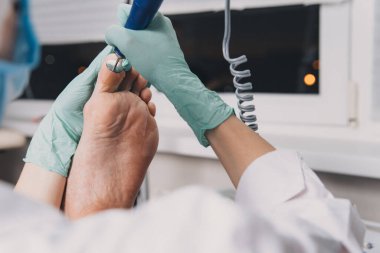 Hırdavat pedikür. Elektrikli makine kullanan profesyonel donanım pedikürü. Maske ve eldiven yapımında uzman. Güzellik salonunda pedikür süreci.