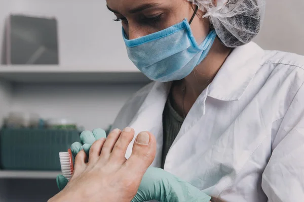 Young woman getting professional pedicure in beauty salon.Master during a pedicure.Master in mask and gloves making pedicure.The process of pedicure in a beauty salon