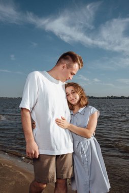 Sahilde birbirine aşık bir çift. Sahilde birbirine aşık bir çiftin portresi. Genç bir kız bir erkeğe sarılıyor. Çift kumsalda romantizm kavramı..