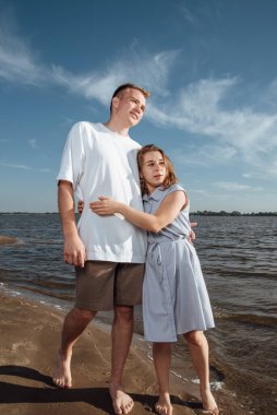 Sahilde birbirine aşık bir çift. Sahilde birbirine aşık bir çiftin portresi. Genç bir kız bir erkeğe sarılıyor. Çift kumsalda romantizm kavramı..