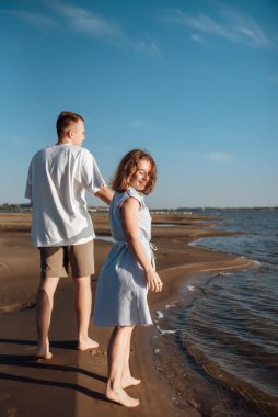 Sahilde aşık bir çift. Kumsalda mutlu genç bir çift. Genç adam ve kadın sahilde yürüyor ve gülüyorlar..