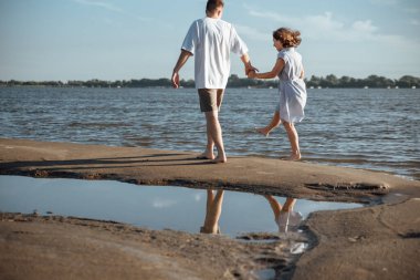 Sahilde aşık bir çift. Kumsalda mutlu genç bir çift. Genç adam ve kadın sahilde yürüyor ve gülüyorlar..