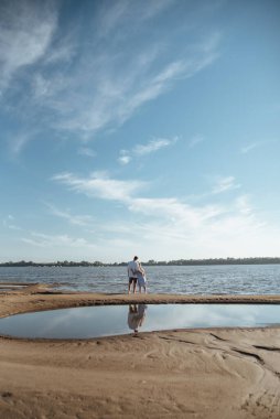Sahilde aşık bir çift. Kumsalda mutlu genç bir çift. Genç adam ve kadın sahilde yürüyor ve gülüyorlar..