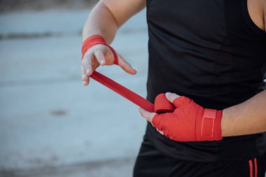 Kırmızı boks bandajlı boksörün eli. Boksör, antrenmandan önce bandajı eline bağlar.