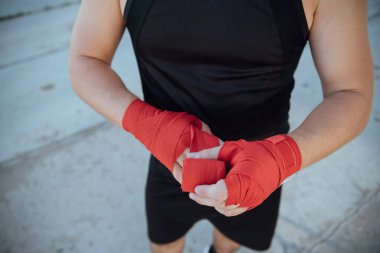 Kırmızı boks bandajlı boksörün eli. Boksör, antrenmandan önce bandajı eline bağlar.