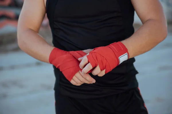 Closeup male hand of boxer with red boxing bandages.Boxing man binds the bandage on his hand, before training, detail photo