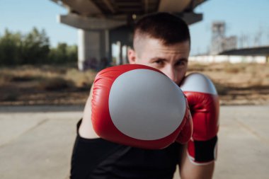 Kırmızı boks eldivenli bir adam. Boks eldivenlerinde boksör eğitimi. Tempo, saldırı ve hareket kavramı.