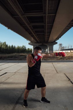 Kırmızı boks eldivenli bir adam. Boks eldivenlerinde boksör eğitimi. Tempo, saldırı ve hareket kavramı.