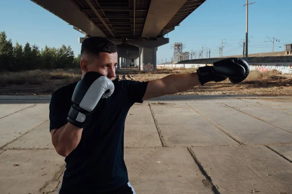 Man in black boxing gloves.Man boxer training in boxing gloves.Strength, attack and motion concept.Sporty man during boxing