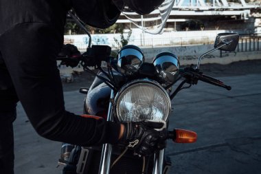 Kasklı motosikletçi motosikleti bir paçavra ile temizler ve motosikletini yıkar.