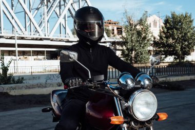 Motosiklette erkek koltuğu. Kasklı adam motosiklette poz veriyor. Siyah kasklı motosikletli adam kırmızı bisikletli.