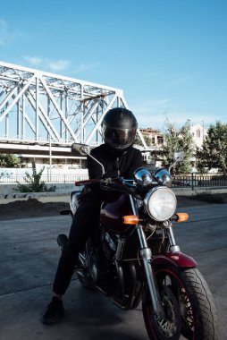 Motosiklette erkek koltuğu. Kasklı adam motosiklette poz veriyor. Siyah kasklı motosikletli adam kırmızı bisikletli.