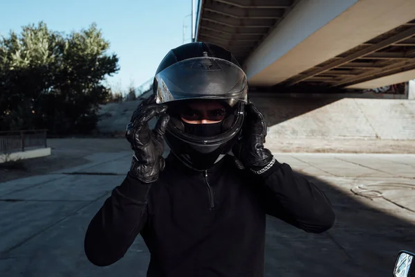 一个英俊的自行车手把他的头盔系紧了 骑摩托车的人戴上头盔 — 图库照片