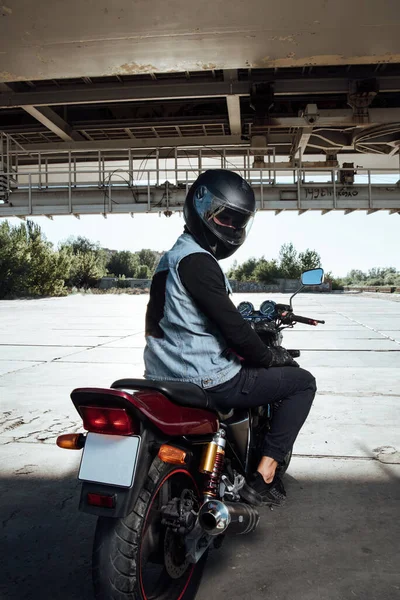 オートバイの男の座席ヘルメットの男はオートバイの上にポーズ 赤い自転車の黒いヘルメットのオートバイの男 — ストック写真