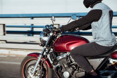 Adam şehirde motosiklet sürüyor. Kasklı ve teçhizatlı genç adam yolda motosiklet sürüyor. Gün boyunca bisiklet sürüyor.