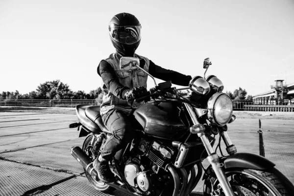 男は街でオートバイに乗ります ヘルメットや機器の若い男は 道路上のオートバイに乗ります オートバイは 道路上の日の間に自転車に乗ります 黒と白の写真 — ストック写真
