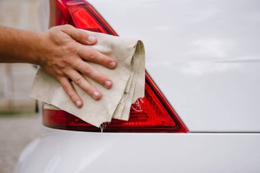 Mikrofiber bezle araba temizleyen bir adam, araba temizleme konsepti. Seçici odaklanma. Temizlik arabasını mikrofiber bezle cilalayan adam.