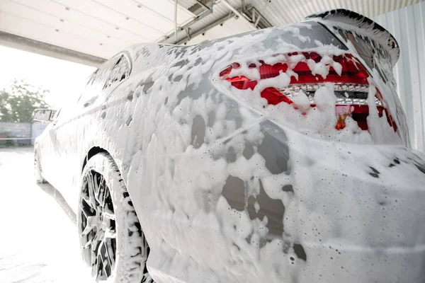 Car wash with soap.Car getting a wash with soap, car washing.Soaping with foam on car in self-service car wash.
