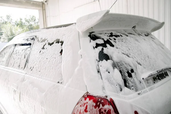 Car wash with soap.Car getting a wash with soap, car washing.Soaping with foam on car in self-service car wash.