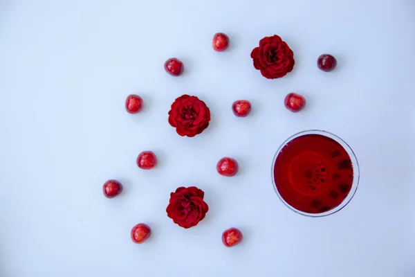 Ένα Ποτήρι Κόκκινο Ποτό Ώριμα Κεράσια Ευωδιαστά Τριαντάφυλλα Λευκό Φόντο — Φωτογραφία Αρχείου
