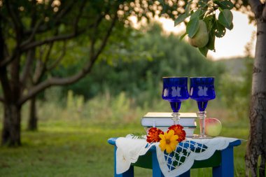 İki cam mavi gözlük, iki kitap, bir elma ve bir tabure üzerinde bir masa örtüsü ile süslenmiş çiçekler bir ağaç üzerinde olgun bir armut ile bir yaz bahçesinde yer almaktadır.