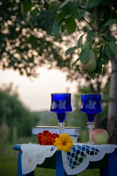 İki cam mavi gözlük, iki kitap, bir elma ve bir tabure üzerinde bir masa örtüsü ile süslenmiş çiçekler bir ağaç üzerinde olgun bir armut ile bir yaz bahçesinde yer almaktadır.