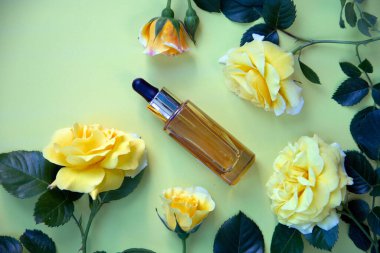 Doğa kozmetik ürünleri cam şişede, pipetli ve sarı güllü. Cilt bakımı için bitkisel özlerle serum. Sağlık ve güzellik kavramı. Düz yat, boşluğu kopyala.