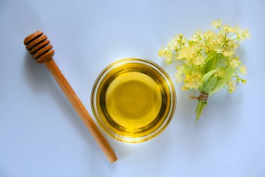 Ballı cam tabak, bal için yuvarlak bir tahta sopa, bir buket çiçek açan ıhlamur. Sağlıklı gıda konsepti. Düz yat, boşluğu kopyala.