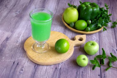 Meyve, sebze ve sebzelerden yapılmış yeşil meyve püresi. Bir bardak vejetaryen içeceği ve ahşap arka planda malzemeler. Superfood sağlıklı detoks ve diyet gıda konsepti.