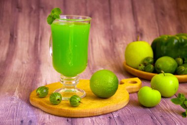 Meyve, sebze ve sebzelerden yapılmış yeşil meyve püresi. Bir bardak vejetaryen içeceği ve ahşap arka planda malzemeler. Superfood sağlıklı detoks ve diyet gıda konsepti.