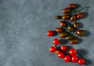 Çeri domateslerinin olgunlaşmış dallarıyla dizilmiş. Yaratıcı kopya alanı olan asgari doğa konsepti. Sağlıklı gıda konsepti. Üst manzara, düz uzanma.