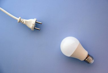 Ampulü ve prizdeki fişi mavi arkaplanda saklayan enerji. Enerji tasarrufu kavramı.
