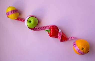 Pembe arka planda mezuralı taze meyve ve sebzelerle moda. Aralıklı, keto, detoks ve ince diyetler. Sağlıklı beslenme konsepti. Düz yat, boşluğu kopyala.