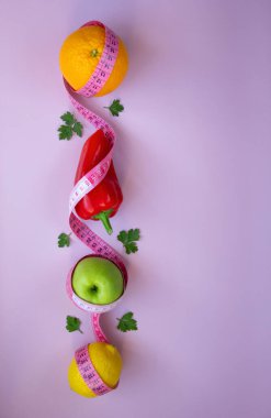Pembe arka planda mezuralı taze meyve ve sebzelerle moda. Aralıklı, keto, detoks ve ince diyetler. Sağlıklı beslenme konsepti. Düz yat, boşluğu kopyala.
