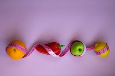 Pembe arka planda mezuralı taze meyve ve sebzelerle moda. Aralıklı, keto, detoks ve ince diyetler. Sağlıklı beslenme konsepti. Düz yat, boşluğu kopyala.