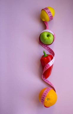 Pembe arka planda mezuralı taze meyve ve sebzelerle moda. Aralıklı, keto, detoks ve ince diyetler. Sağlıklı beslenme konsepti. Düz yat, boşluğu kopyala.