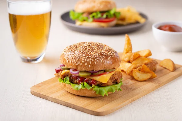 Burger with sliced pickle, onion and fried potatoes, drink