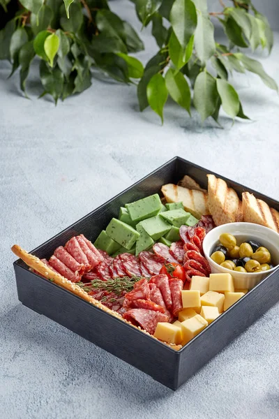 Set of snacks: sausage, salami, tomato, cheese, green olive, bread in black box — Stock Photo, Image