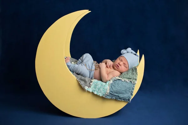 工作室肖像十天的新生儿婴儿穿着睡衣底部和一个睡觉帽 他在月亮形状的道具上睡觉 — 图库照片