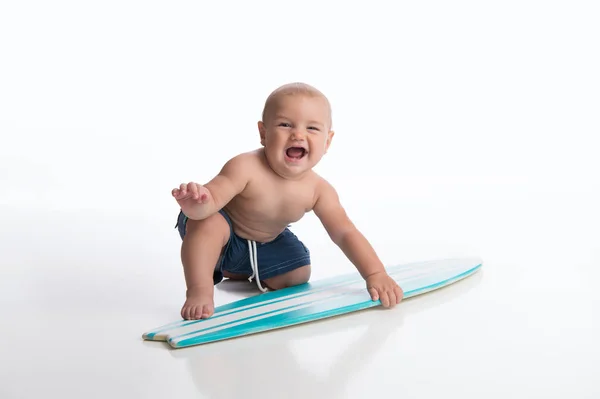 一个笑七月大的小男孩玩一个小冲浪板 拍摄在演播室在白色 无缝的背景 — 图库照片