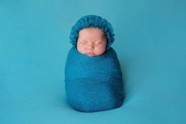 ターコイズ ブルー ボンネットを身に着けている 週齢の新生児の女の子で ストレッチ ラップで Swaddled 彼女は真っ直ぐ寝ています — ストック写真