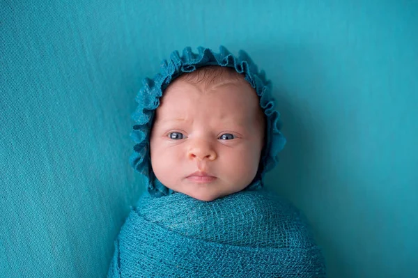 Förbryllad nyfödd flicka klädd i en turkos blå motorhuven — Stockfoto