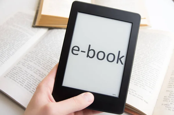 Segurando ebook na frente de livros antigos com texto EBOOK — Fotografia de Stock