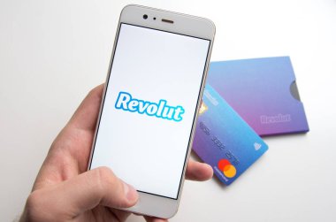 Arkasında kartları ile telefonda Revolut mobil uygulaması tutma