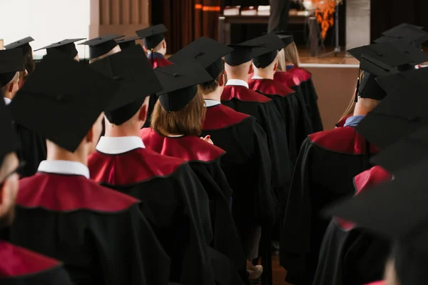 Bir grup yeni üniversite mezunu cübbe ve şapkayla törenle mezun oluyor. — Stok fotoğraf