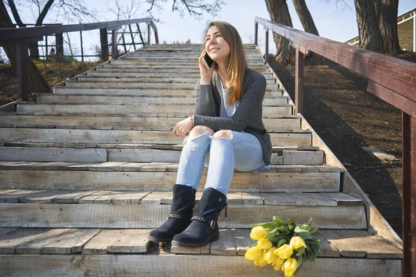 Frau mit einem Blumenstrauß auf der Treppe sitzend und — Stockfoto