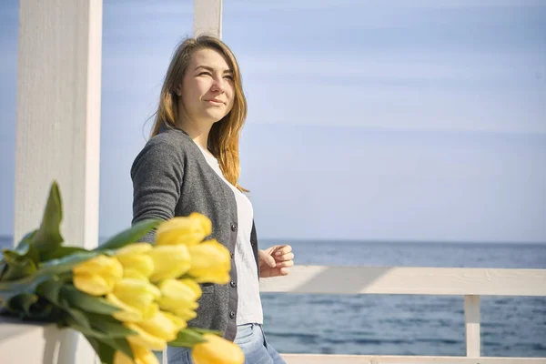 Una ragazza sta con i fiori sullo sfondo del waterfr — Foto Stock